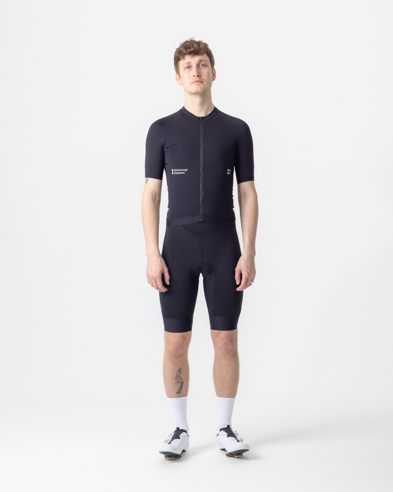 Model wearing the Men's Mono Short Sleeve Jersey in Black, front view, paired with black cycling bib shorts.