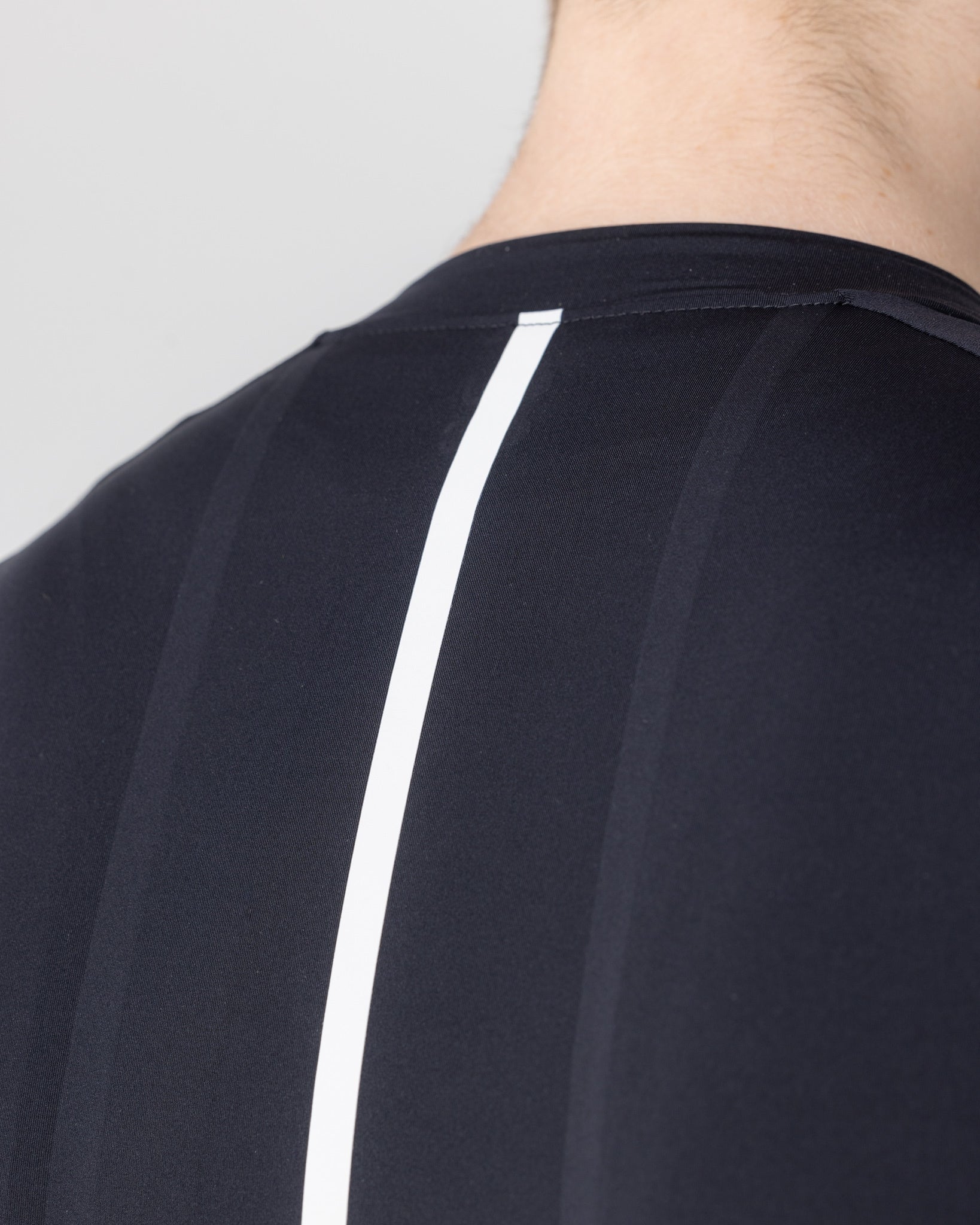 Upper-back close-up: reflective white spine stripe and raglan shoulder seam on the Black Mono Short Sleeve Jersey.