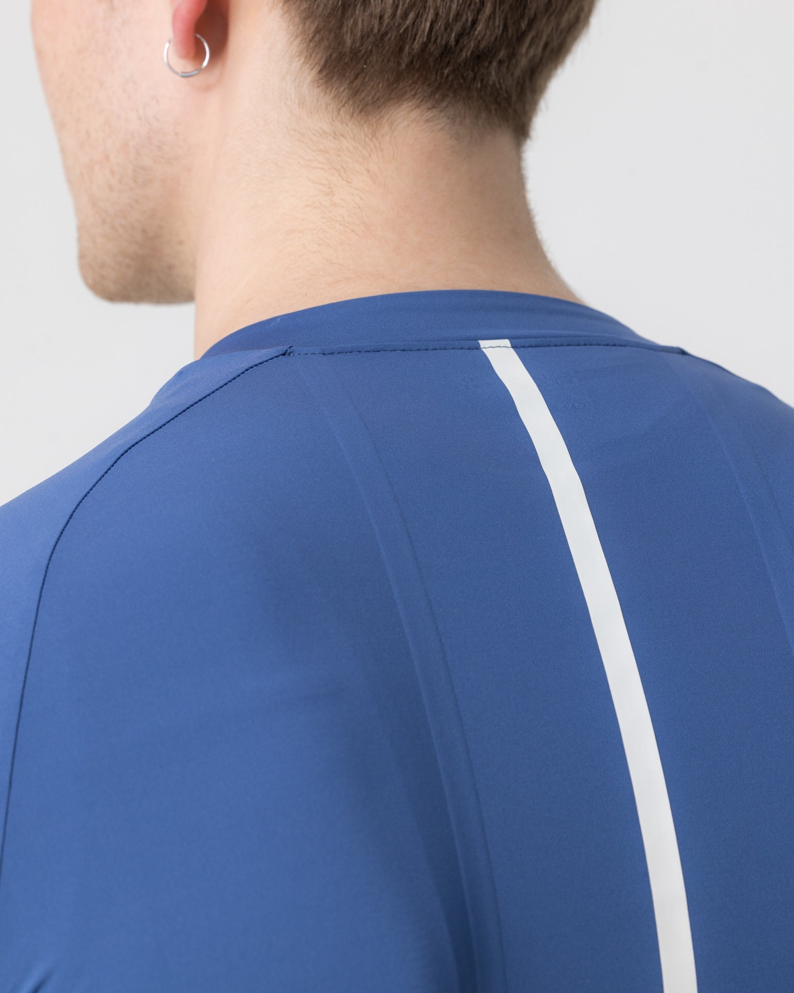 Upper-back close-up: reflective white spine stripe on the French Blue Mono Short Sleeve Jersey, raglan shoulder seam.