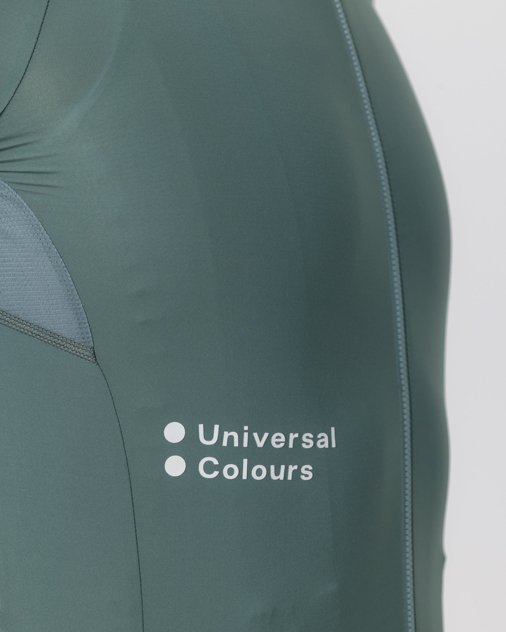 Close-up of the white Universal Colours wordmark and front zip on the Men's Mono Short Sleeve Jersey in Green Daze.