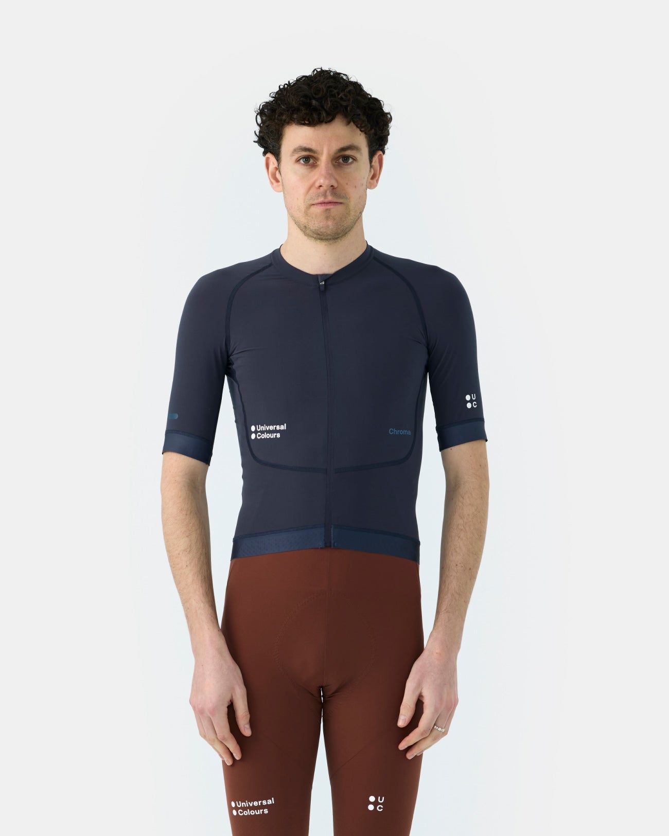 Model wearing the Men's Chroma Short Sleeve Jersey in Midnight Blue, front view, paired with rust-toned bib shorts.