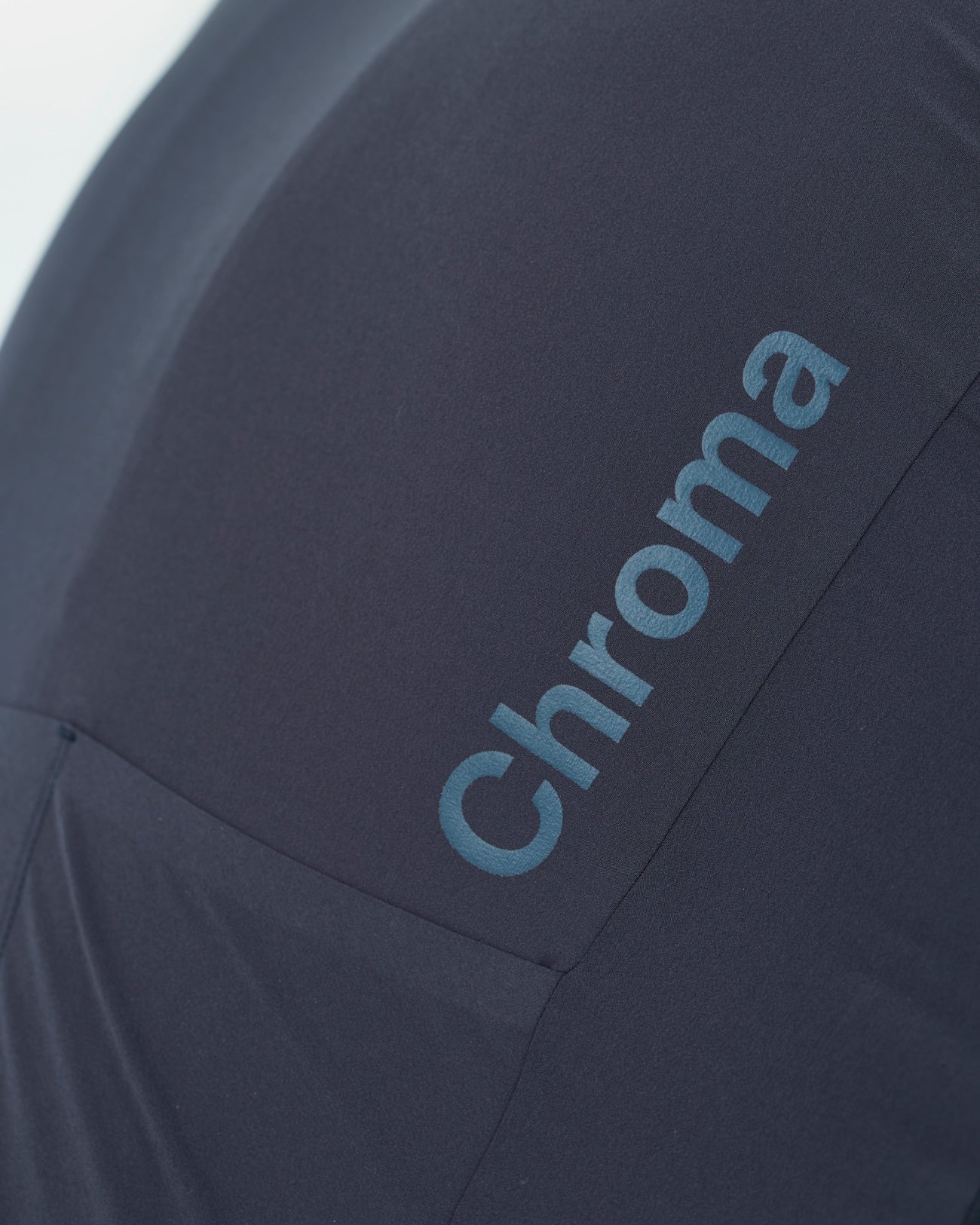 Detail of the tonal Chroma wordmark across the back panel of the Men's Chroma Short Sleeve Jersey in Midnight Blue.