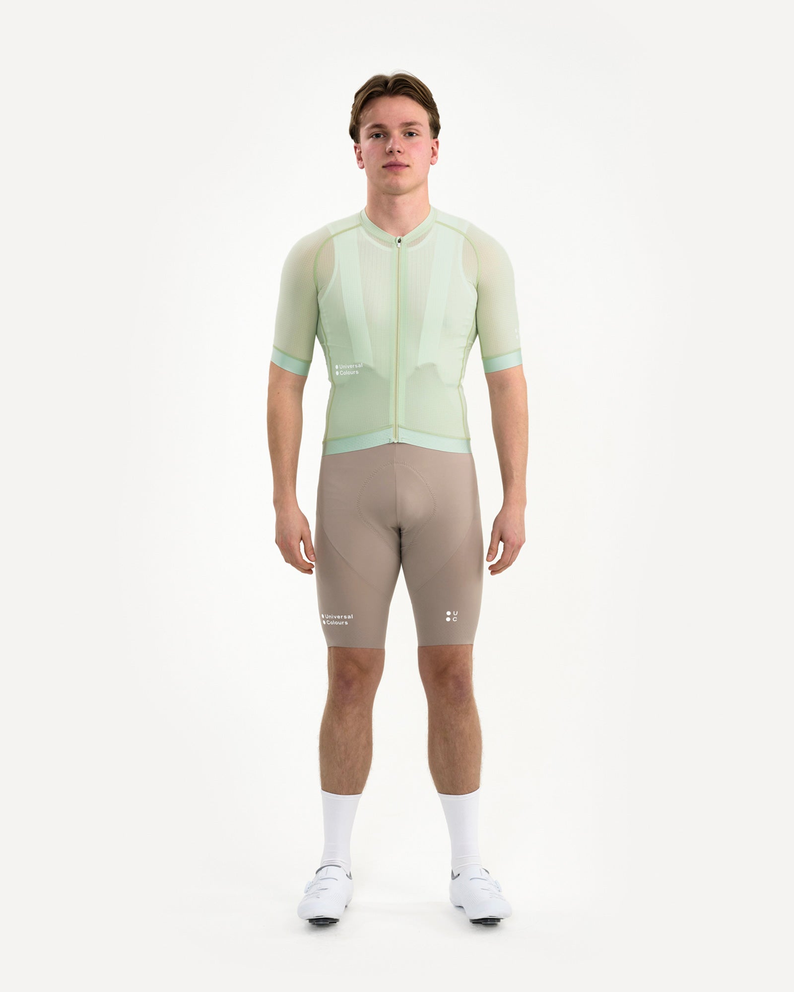 Model wearing the Men's Chroma Light Jersey in Bower Green, paired with mosswood brown bib shorts and white socks.