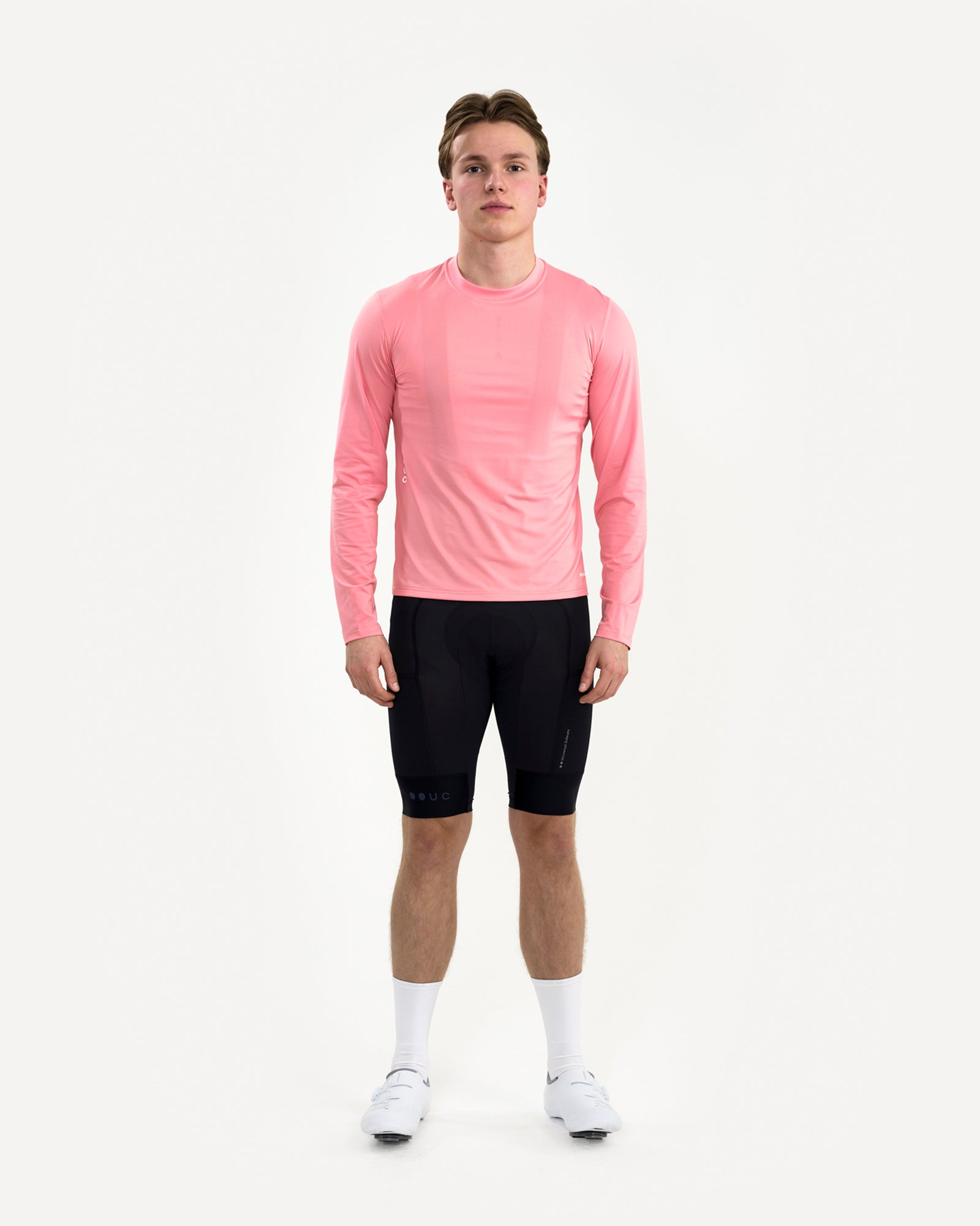 Men's front view of the Long Sleeve Tech Tee in Washed Pink, paired with black UC bib shorts and white road cycling shoes.