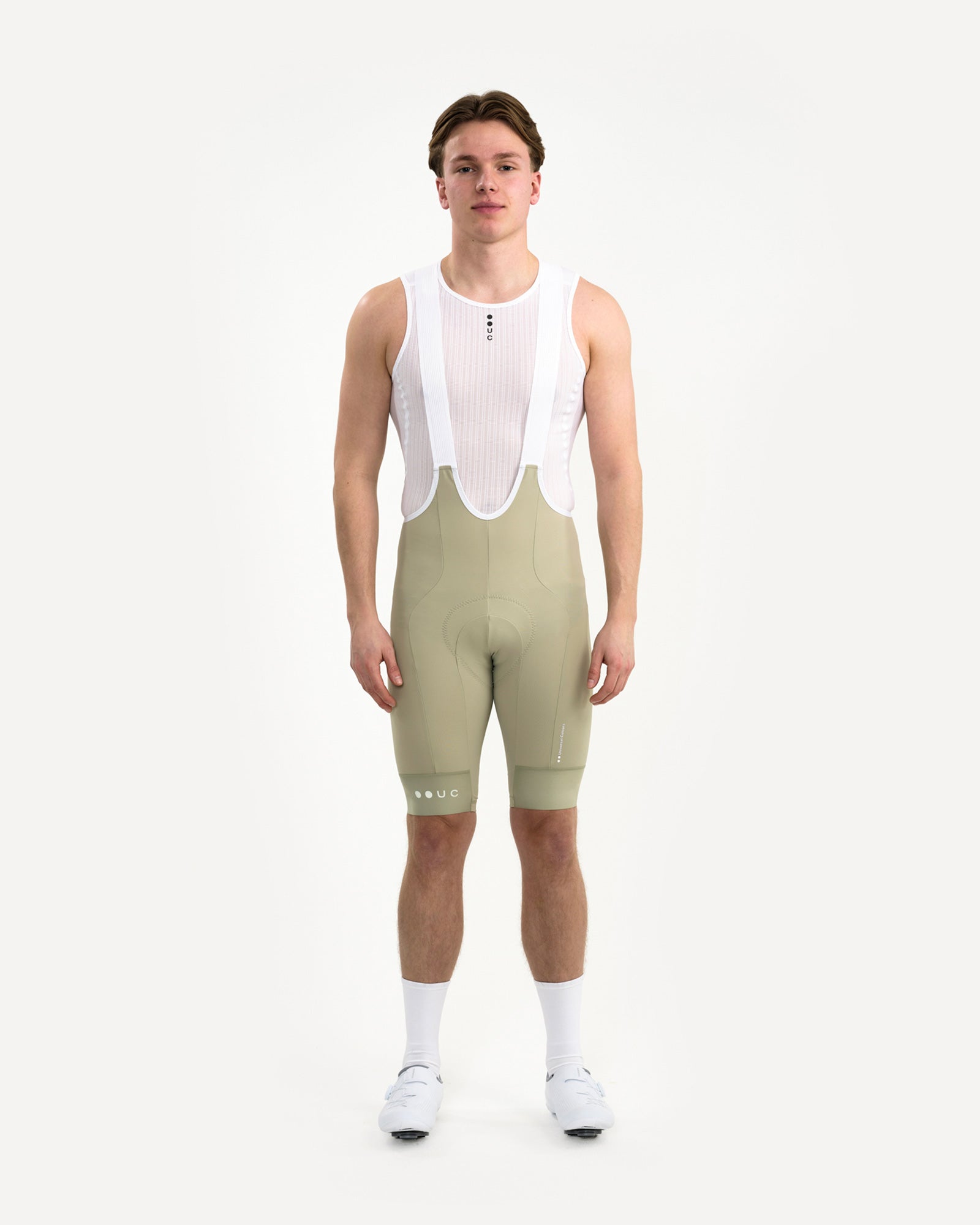 Front view: model in the Men's Mono Bib Shorts 2.0 in Green Tea with white UC mesh base layer, socks and cycling shoes.