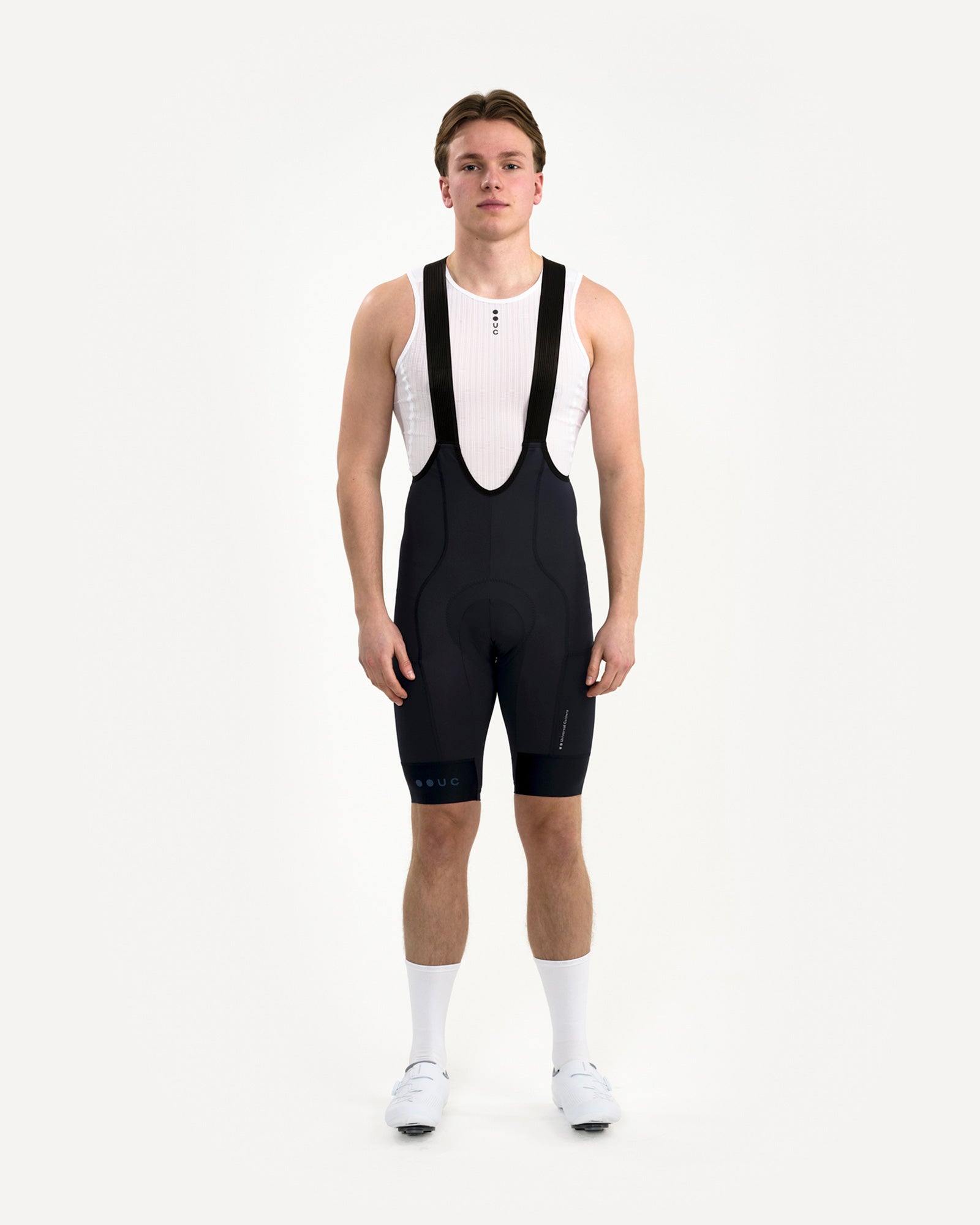 Front view: model in the Men's Mono Cargo Bib Shorts in Navy Blue with white UC base layer, white socks and road shoes.