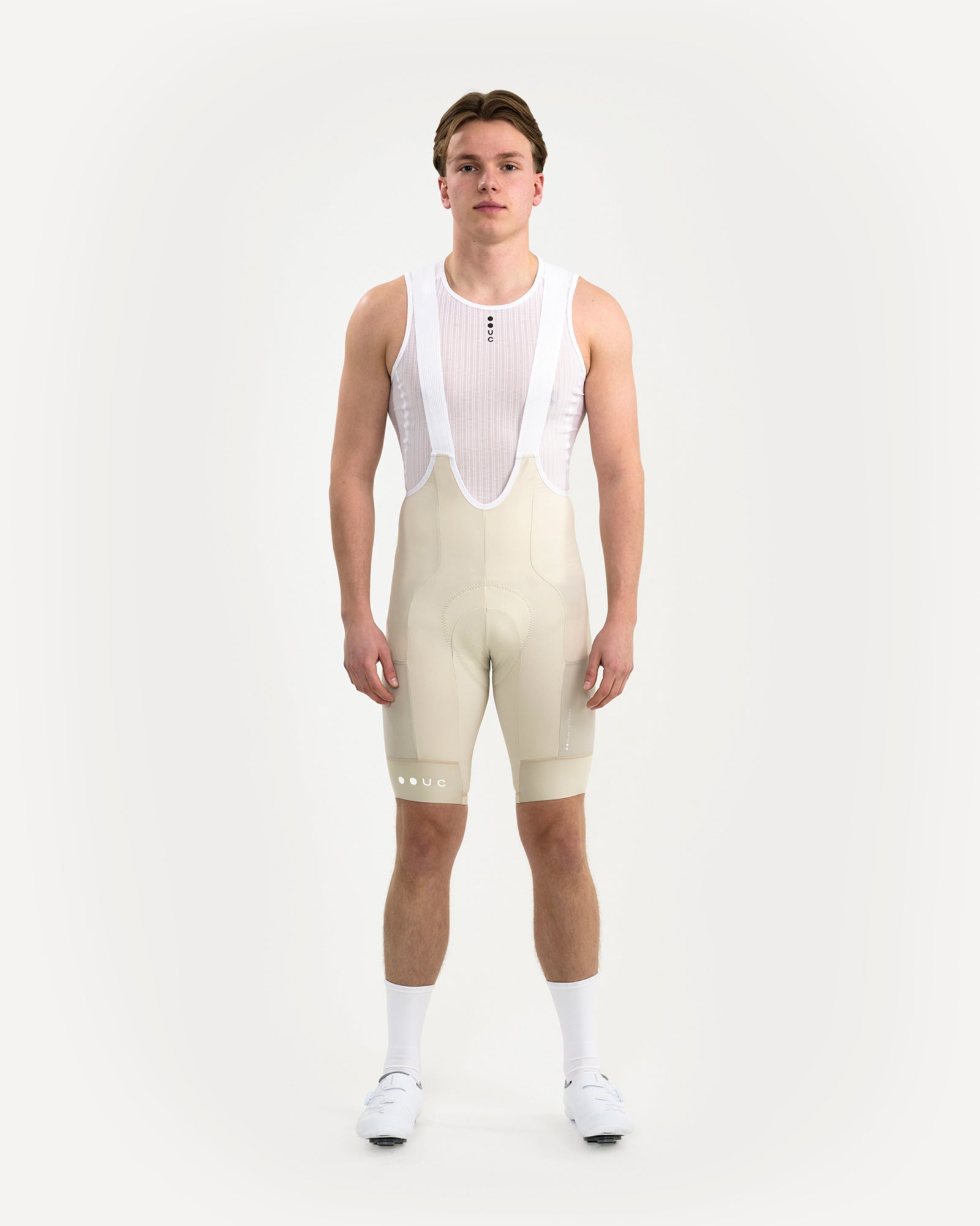 Model wearing the Men's Mono Cargo Bib Shorts in Off White, front view, with white mesh base layer, UC socks and white shoes.