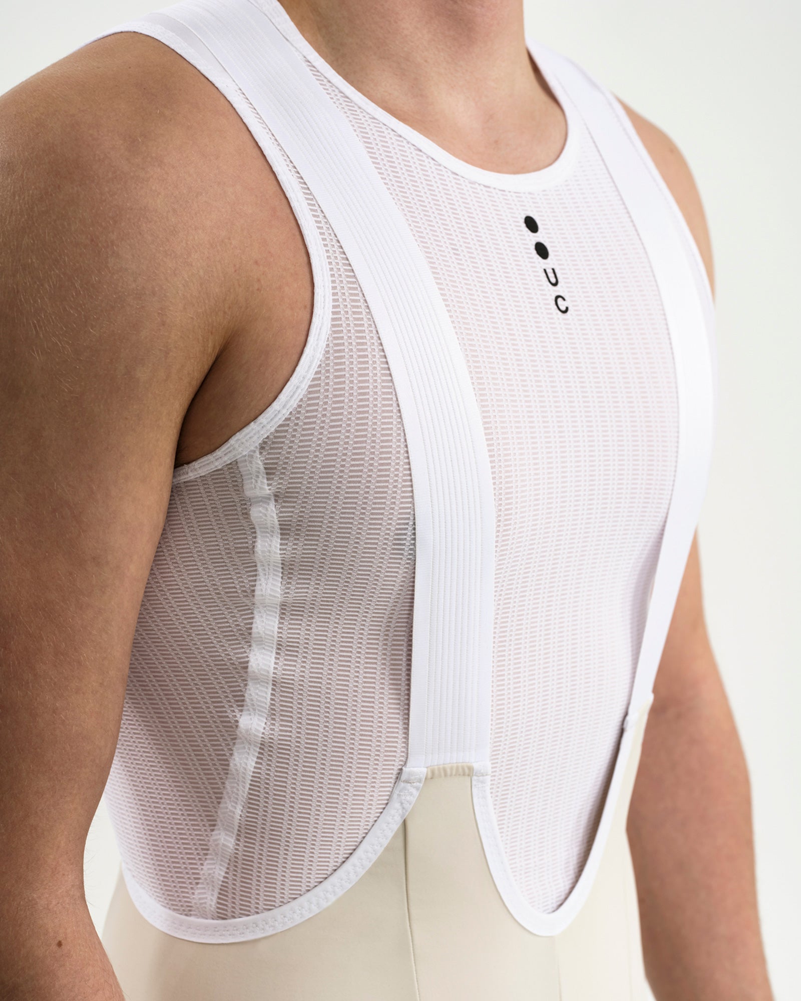 Close-up of the white mesh bib straps of the Men's Mono Cargo Bib Shorts in Off White over a UC ribbed base layer.