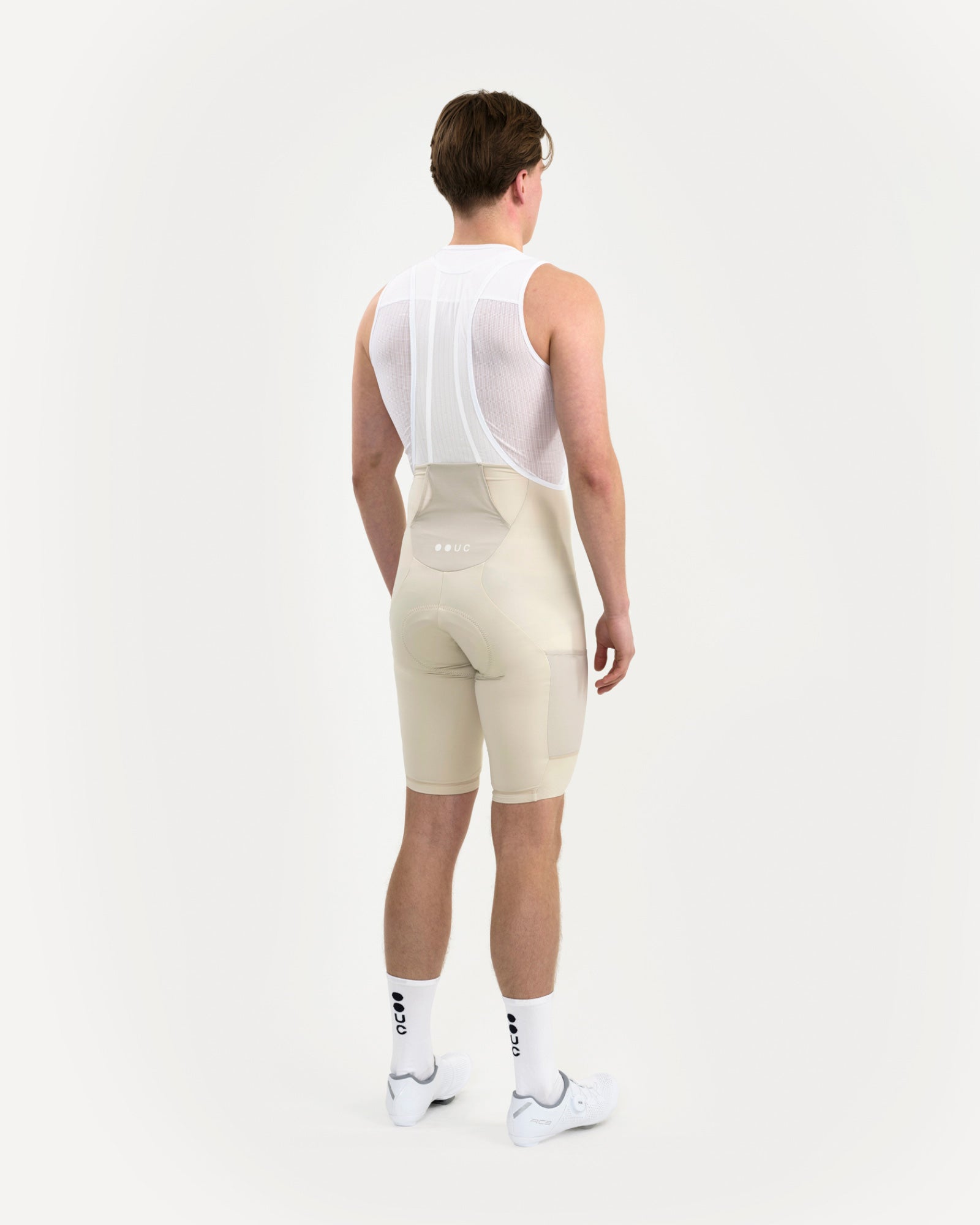 Three-quarter rear view: Men's Mono Cargo Bib Shorts in Off White on model, showing the tonal cargo side pocket on the thigh.