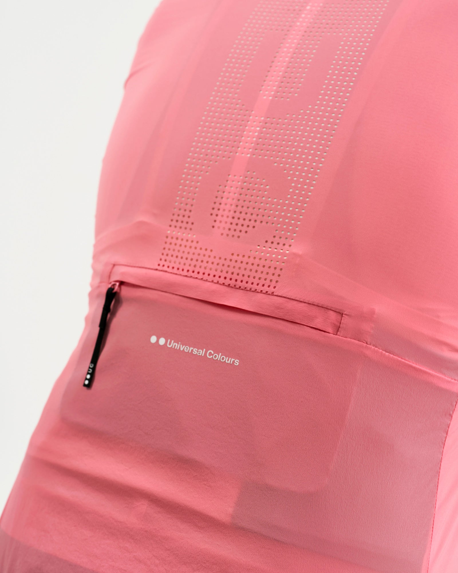 Rear pocket detail: perforated tonal UC dot pattern above the zipped valuables pocket with Universal Colours wordmark.