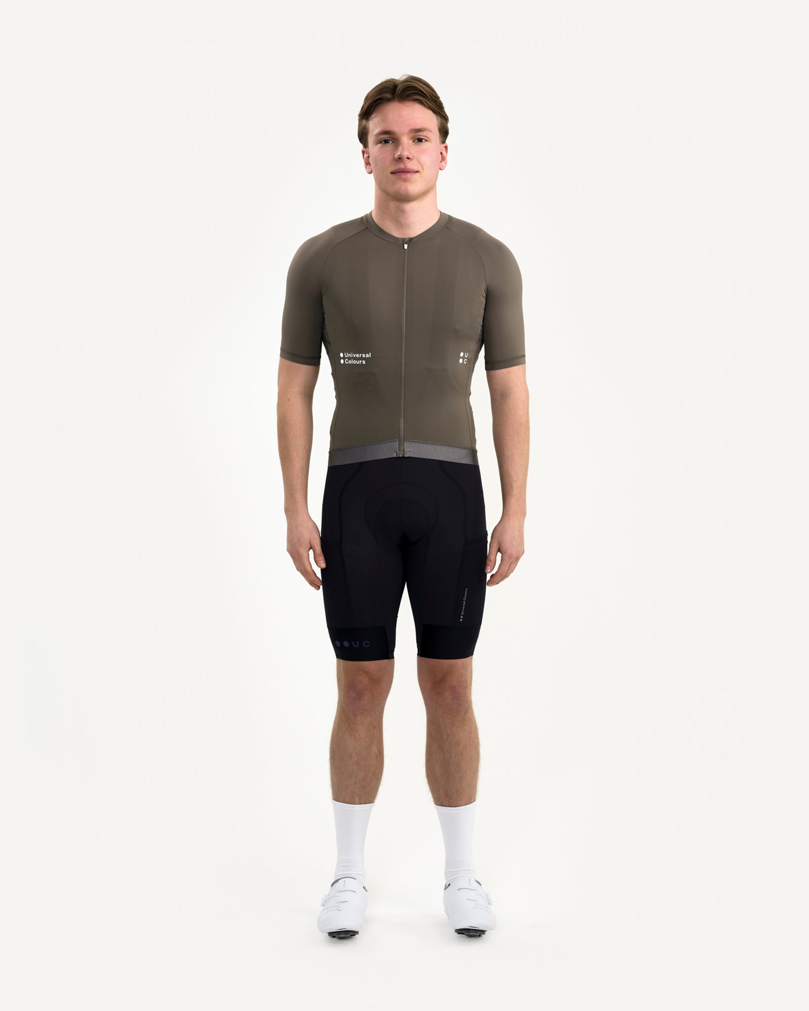 Front view: model in Men's Mono Short Sleeve Jersey in Soft Grey, paired with black bib shorts and white cycling shoes.