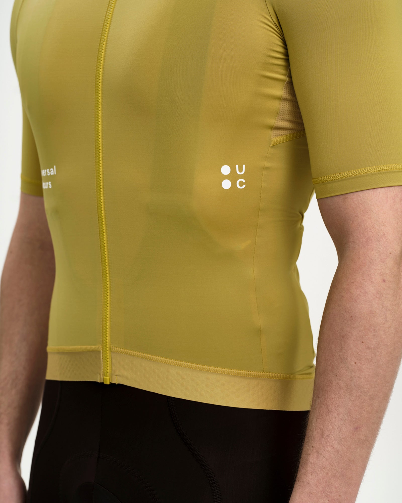 Hem detail of the Men's Mono Short Sleeve Jersey in Acidic Yellow: silicone gripper hem, tonal zip pull and UC roundel.