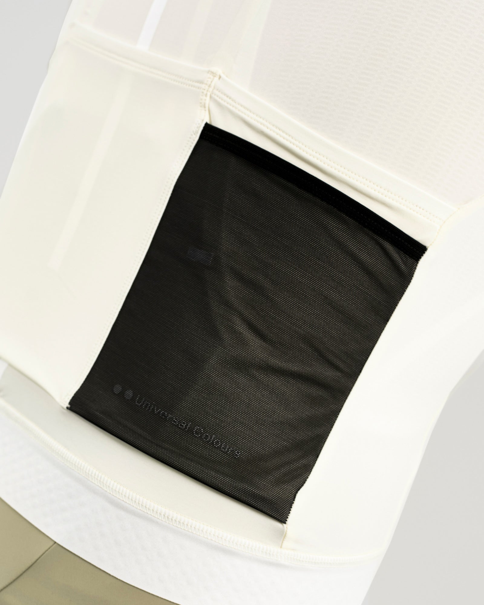 Rear pocket detail: black zipped valuables pocket with tonal Universal Colours wordmark on the Tampered White jersey.