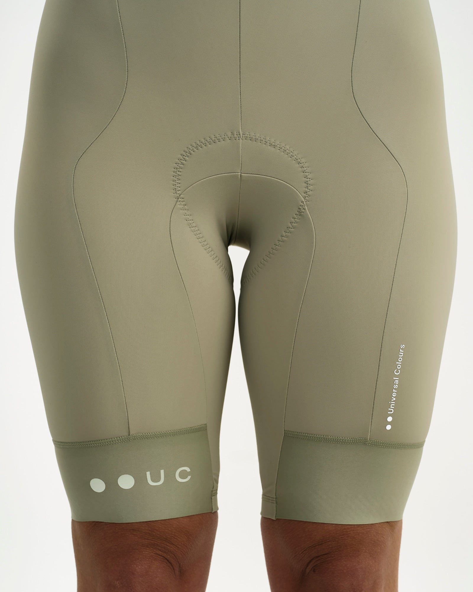 Front leg detail: Women's Mono Bib Shorts 2.0 in Green Tea showing pad seam, thigh wordmark and UC dots hem print.