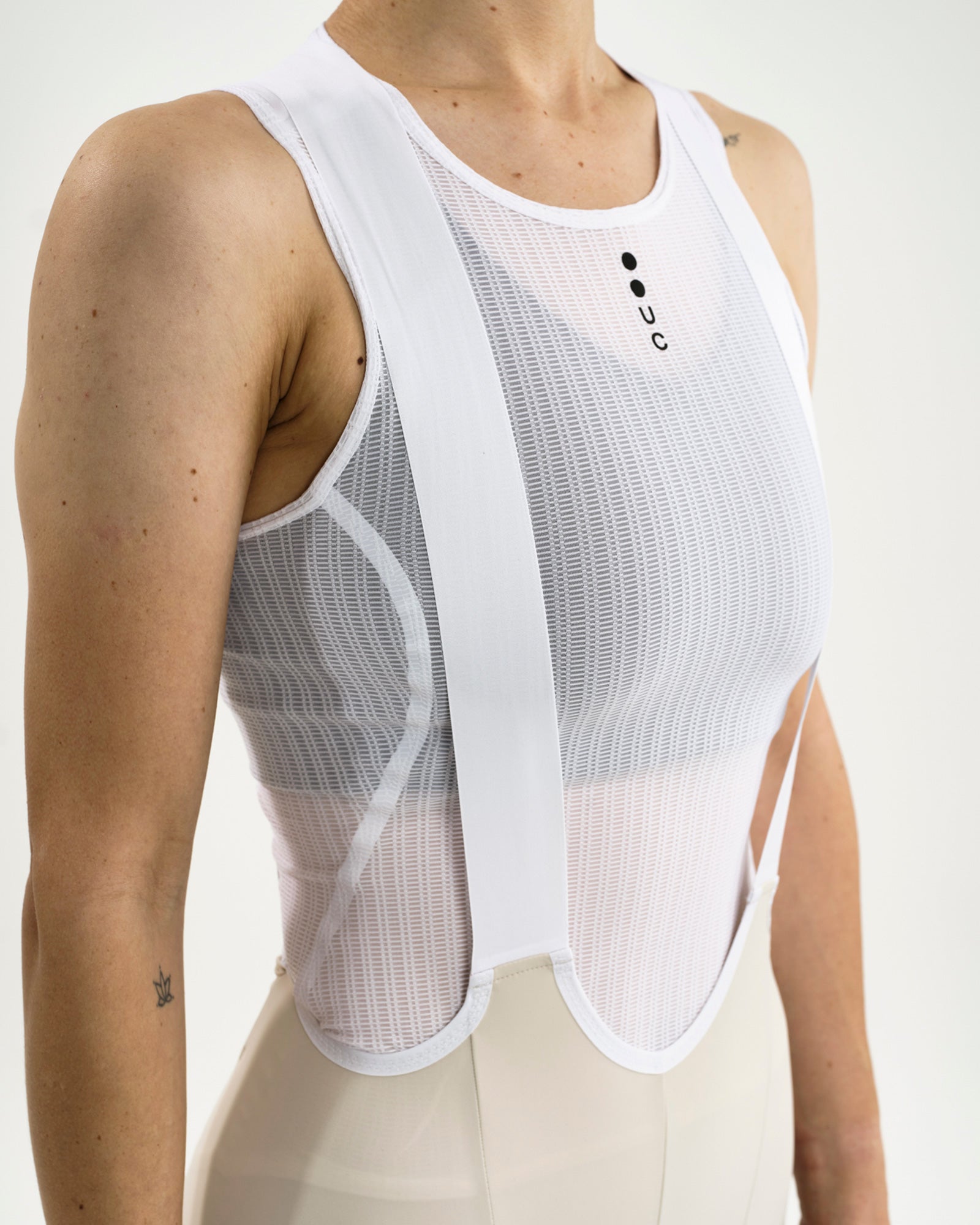 White UC mesh base layer detail: sheer mesh worn over the crossover straps of the Women's Mono Bib Shorts 2.0 in Off White.