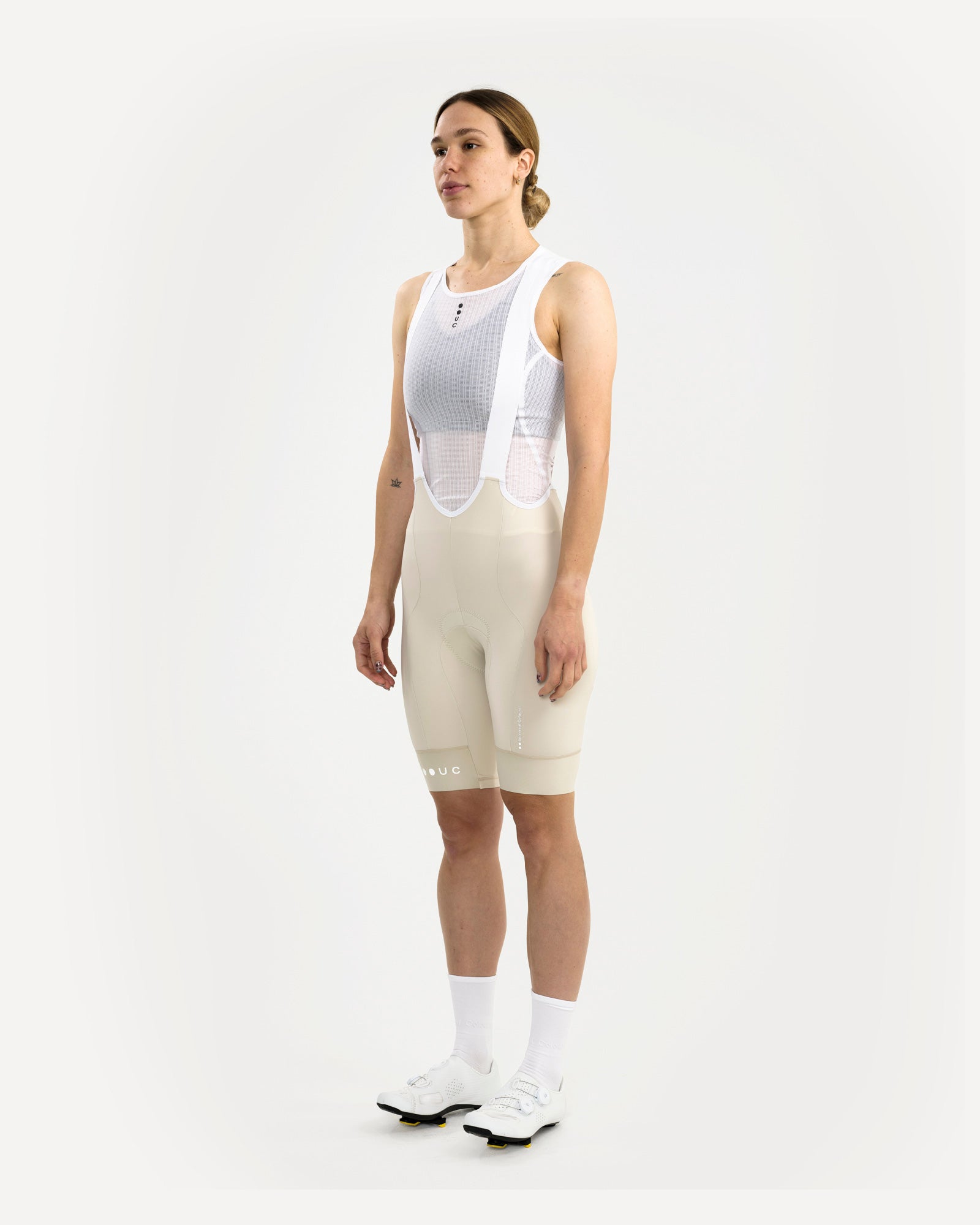 Three-quarter front view: model in the Women's Mono Bib Shorts 2.0 in Off White with white UC mesh base layer and shoes.