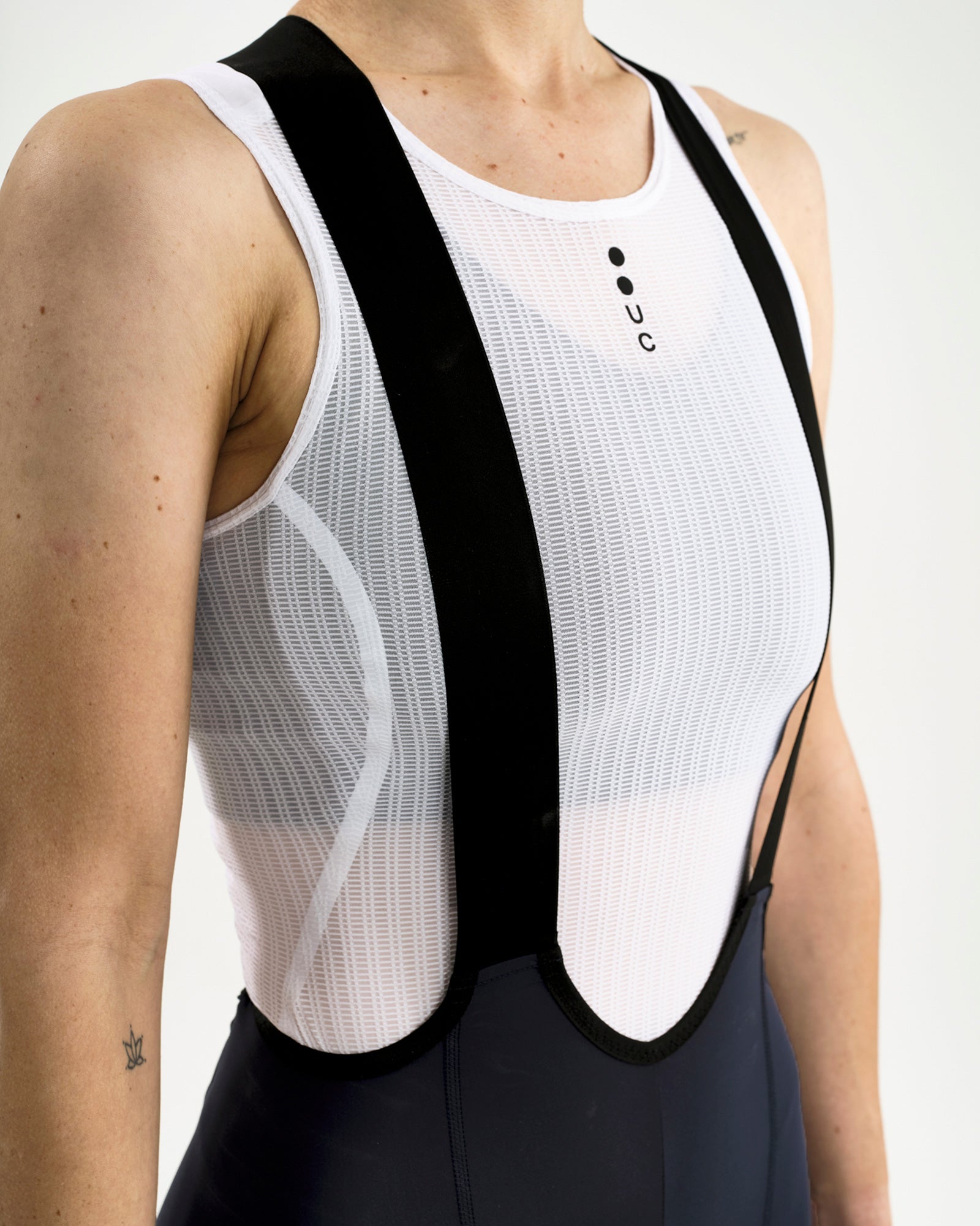 Close-up of the X-cross bib straps and white UC mesh base layer over the Women's Mono Cargo Bib Short, Navy Blue.