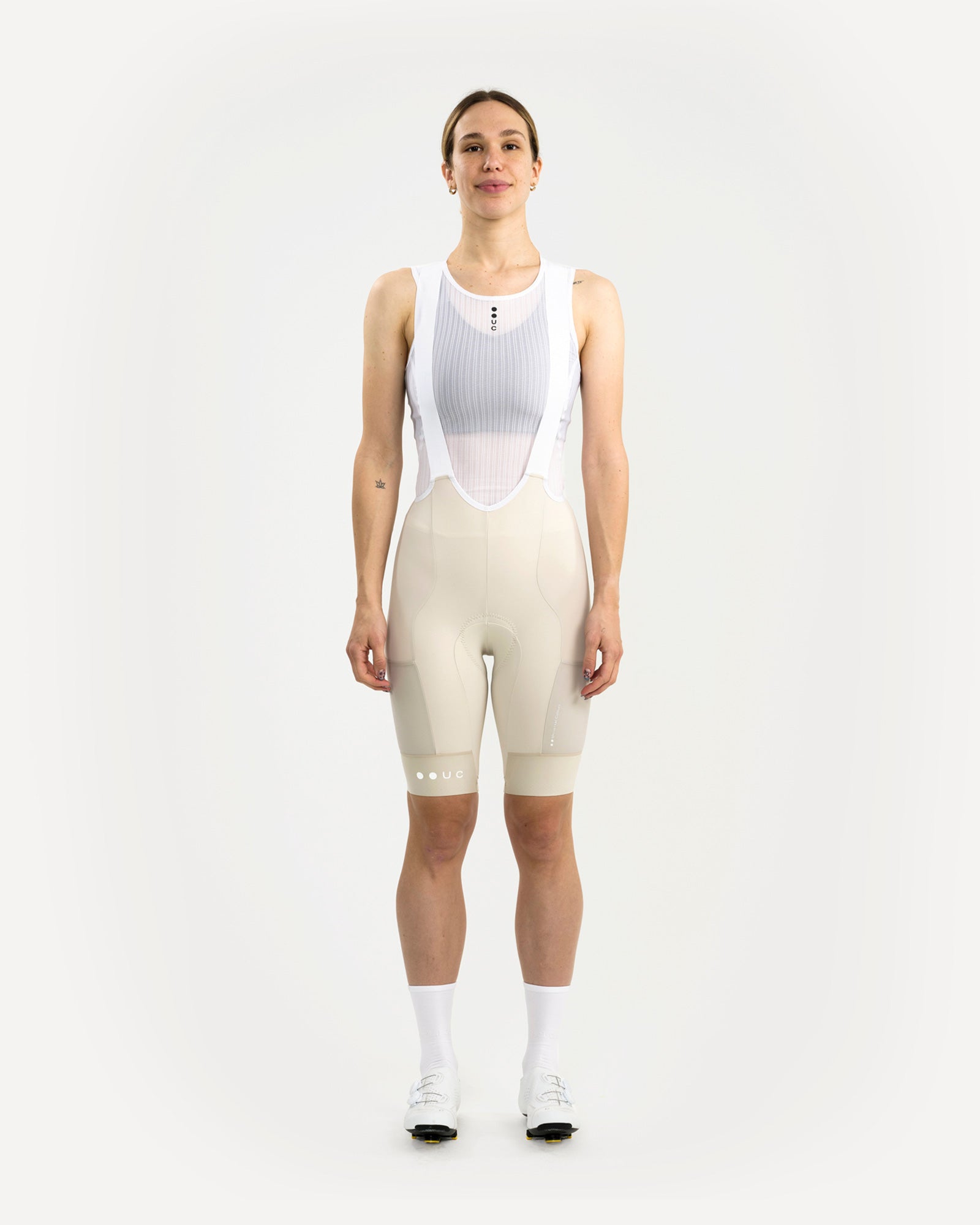 Model front view in the Women's Mono Cargo Bib Short, Off White, with white mesh bib upper and crossover shoulder straps.