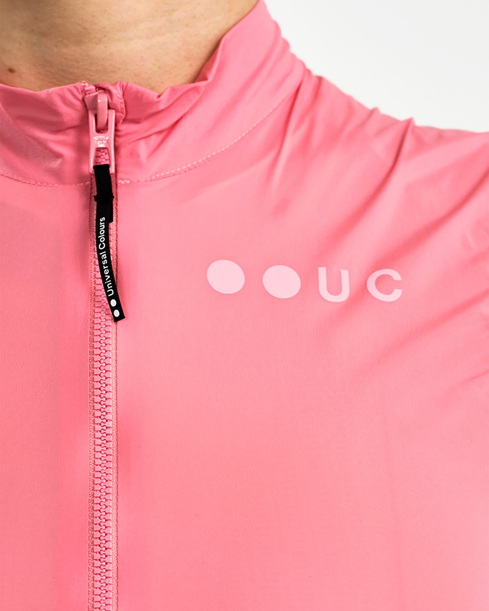 Collar and zip detail on the Women's Mono Gilet 2.0 in Washed Pink: branded Universal Colours zip pull and tonal UC logo.