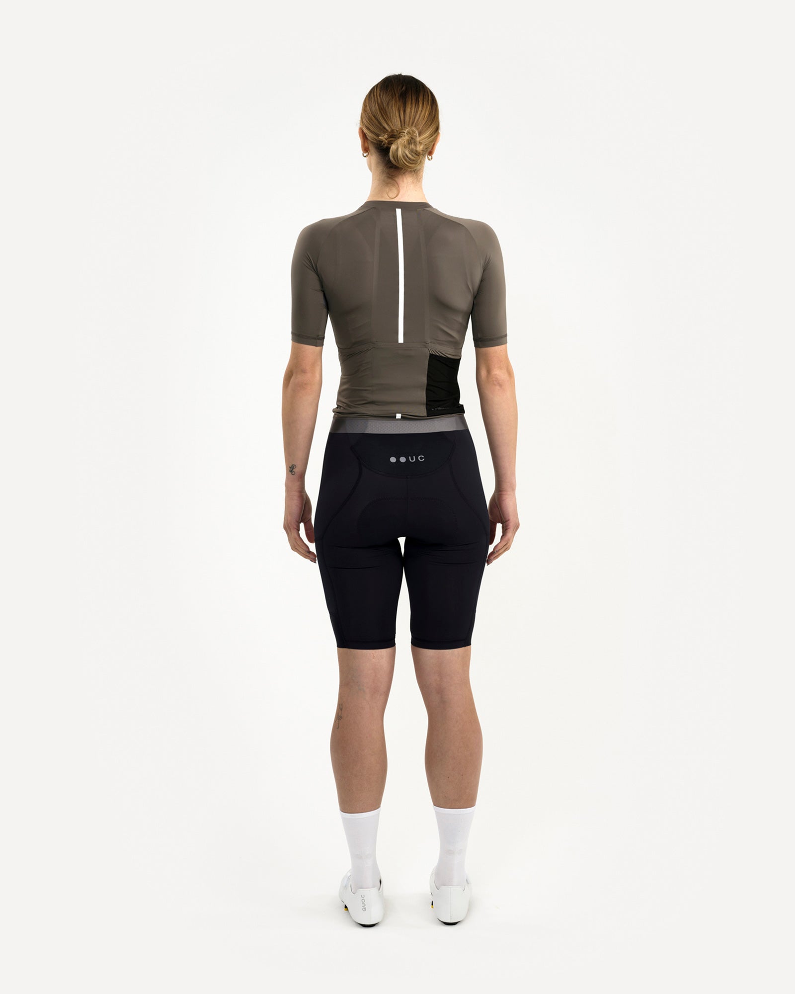 Back view: Women's Mono Short Sleeve Jersey in Soft Grey with vertical reflective stripe, worn with black UC bib shorts.