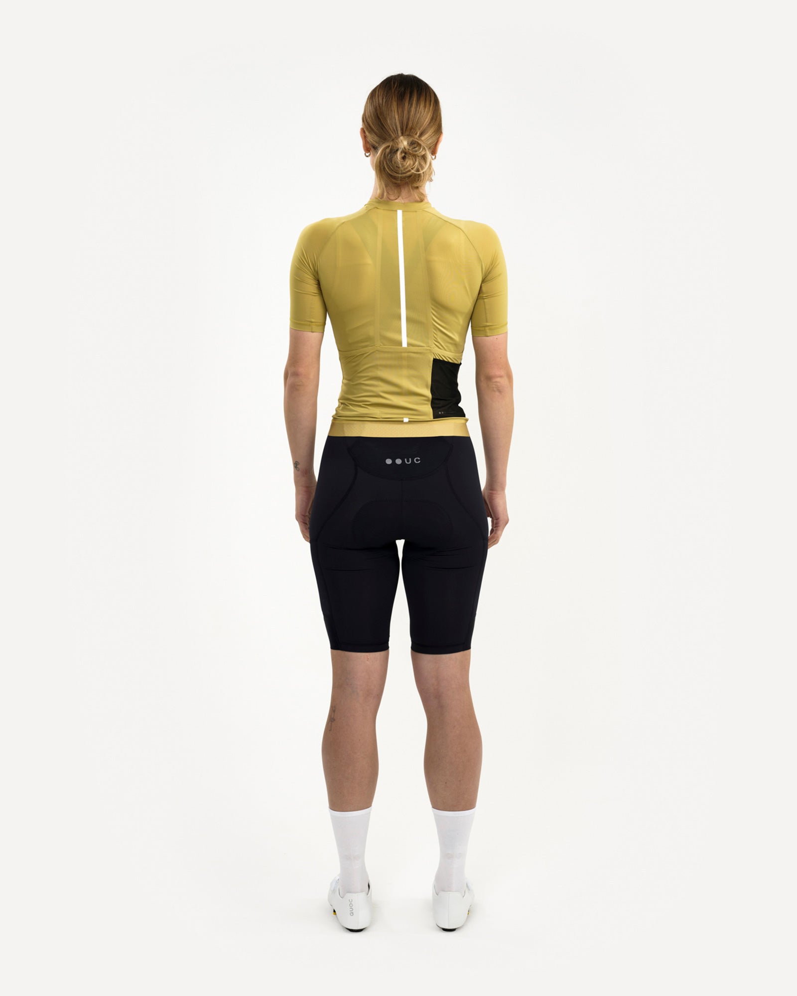 Model wearing the Acidic Yellow Mono Short Sleeve Jersey, back view, with black UC bib shorts and white cycling shoes.
