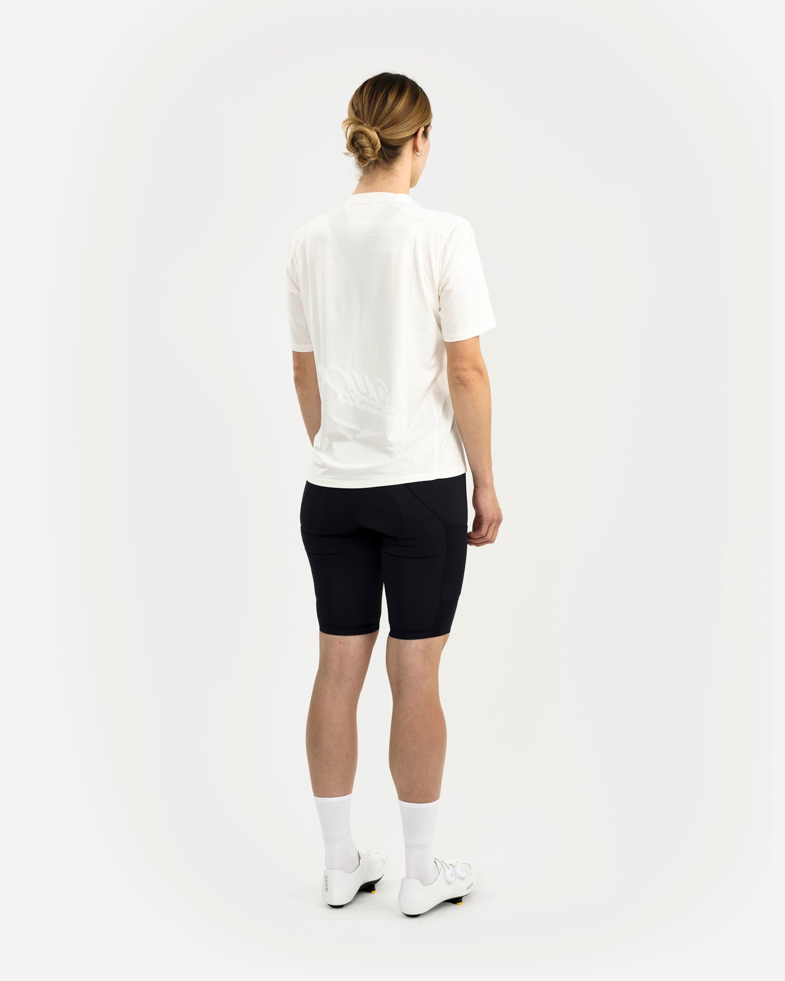 Women's back view of the Tech Tee in Off White, showing the tonal embossed UC script print across the lower back.
