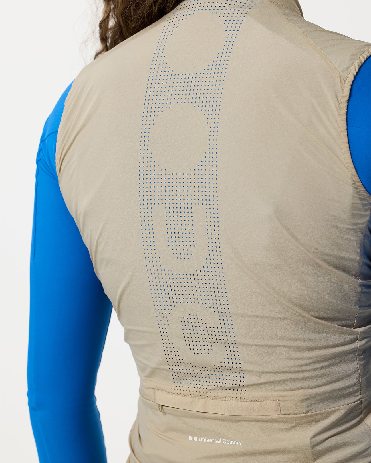 Detail of the large perforated UC graphic across the back panel of the Women's Mono Gilet 2.0 in Rice Beige.