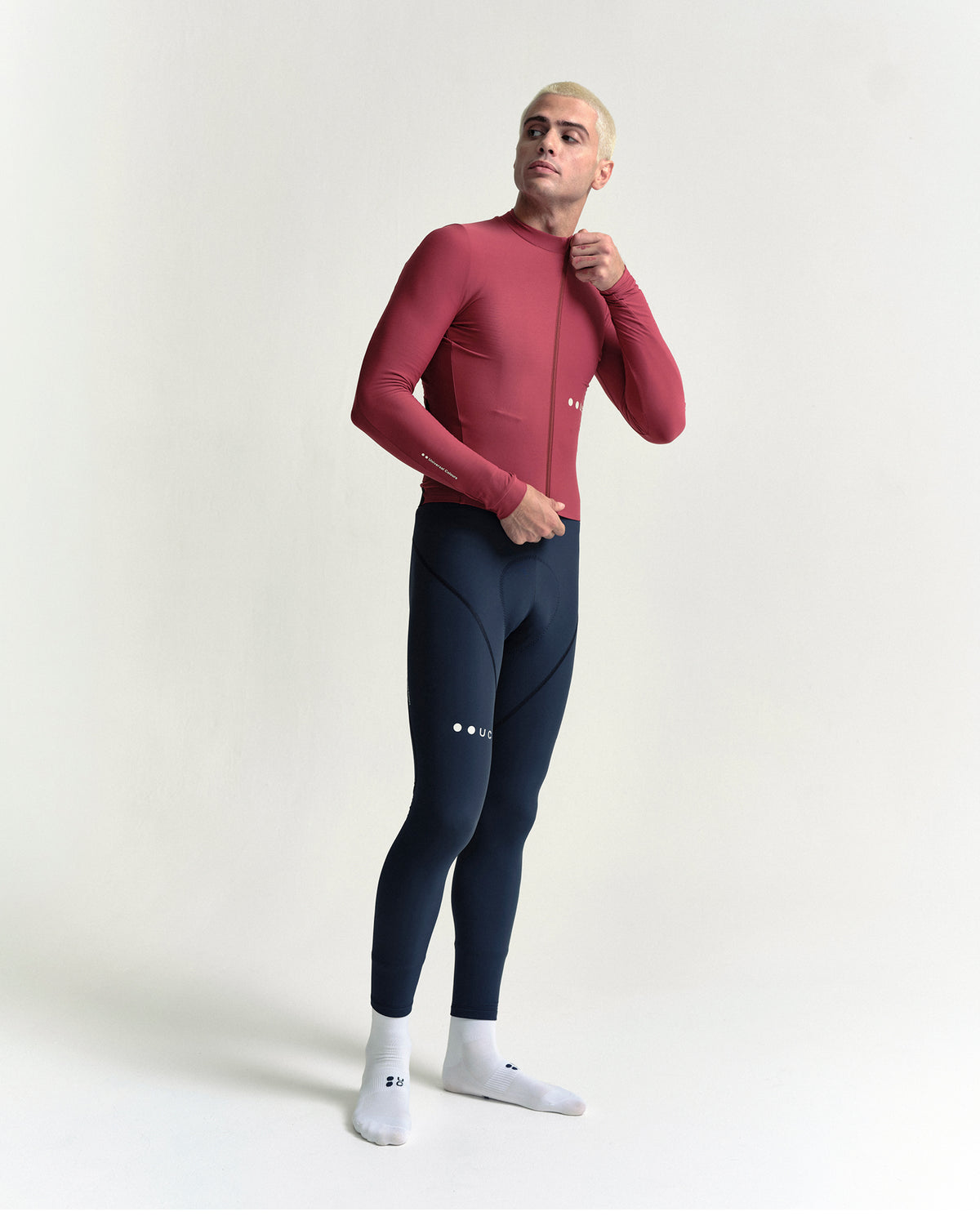 Model zipping the Men's Mono Long Sleeve Jersey in Apple Red, full-length view.