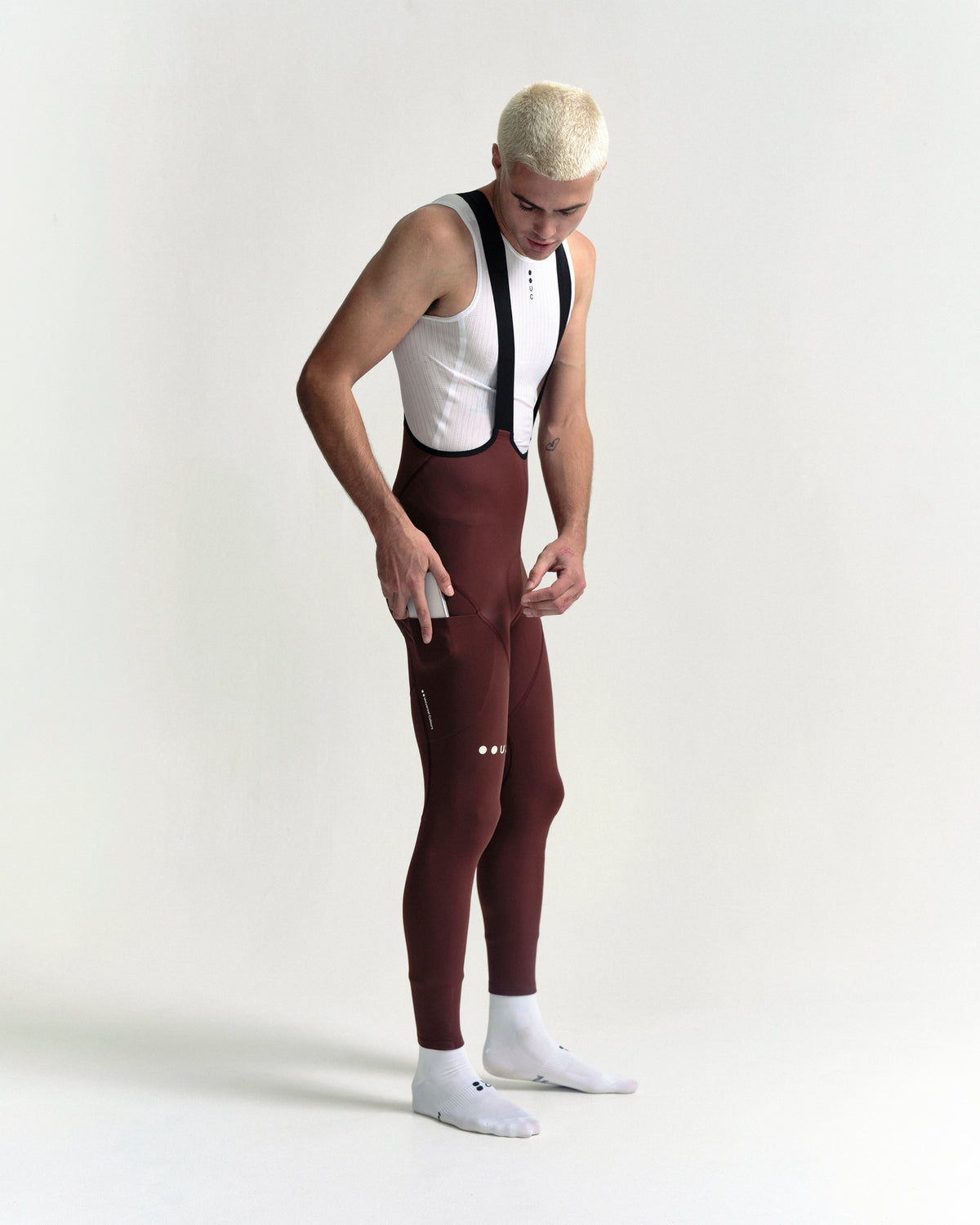 Model in the Men's Mono Cargo Bib Tight in Deep Red, full-length view.