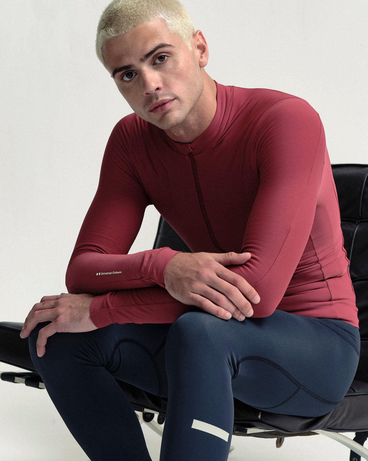 Model seated in the Men's Mono Long Sleeve Jersey in Apple Red.