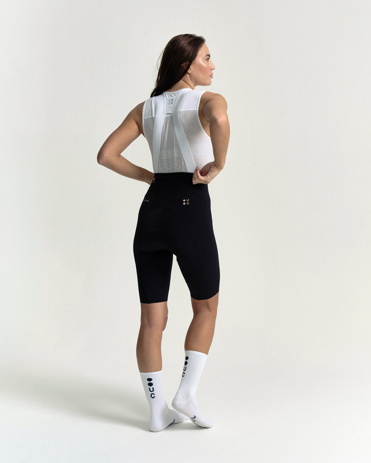 Model in the Women's Chroma Bib Shorts in Black/Bronze, full-length back view.