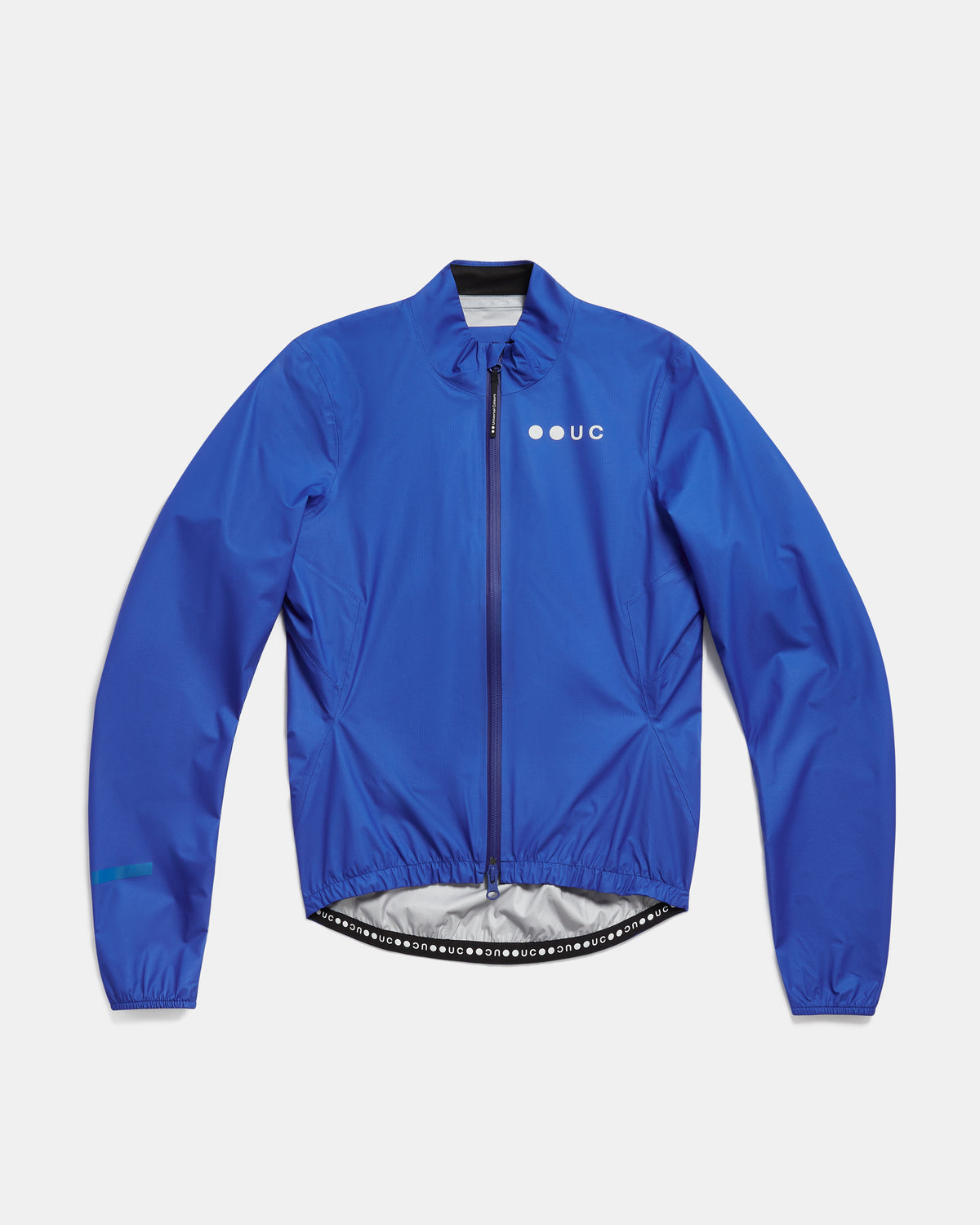 Flatlay of the Women's Mono Rain Jacket in Vivid Blue: high collar, full-length zip, UC chest logo, elasticated hem.