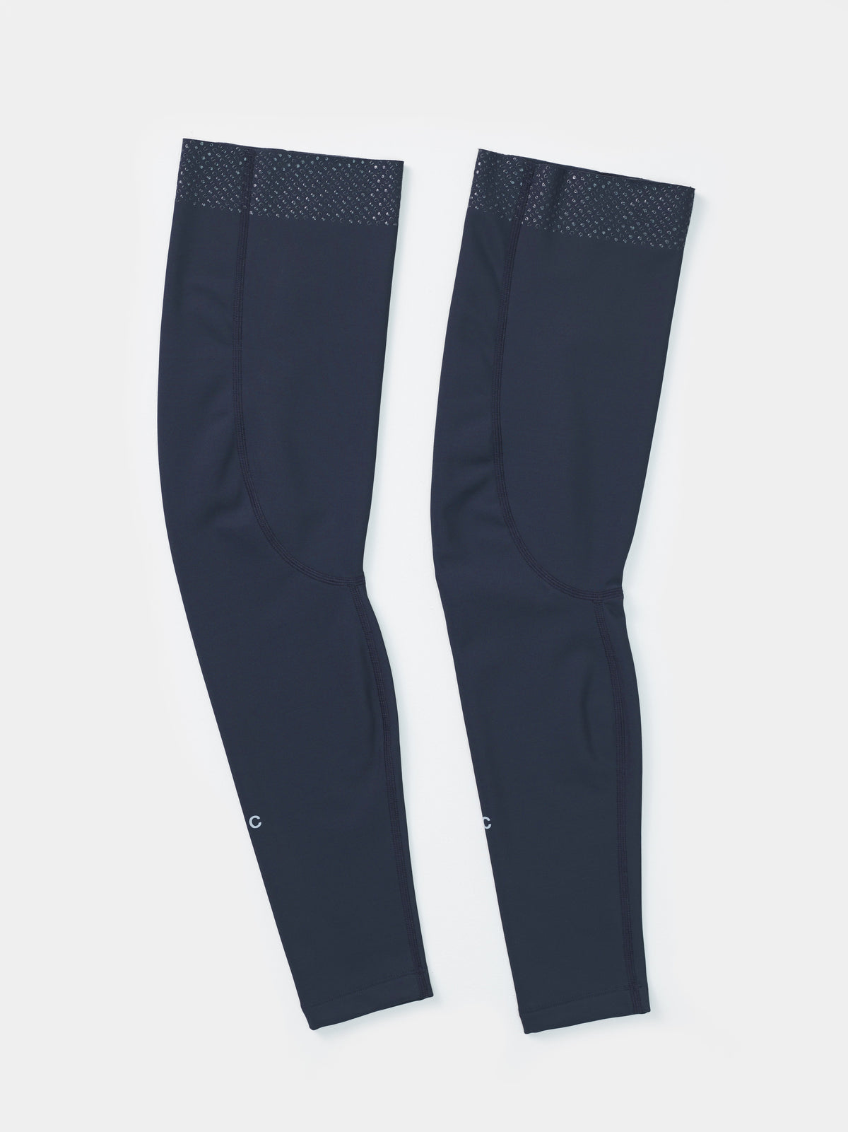Flatlay of the UC Leg Warmers in Eclipse Navy: silicone gripper dots at the top hem and UC wordmark near the cuff.