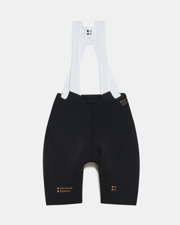 Flatlay of the Women's Chroma Bib Shorts in Black/Bronze: ribbed bib straps, Universal Colours hip print and leg logos.