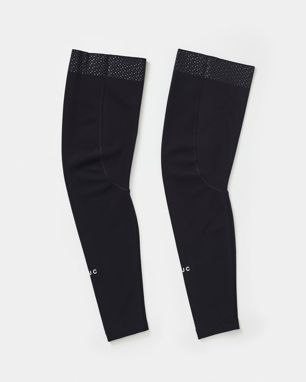 Flatlay of the UC Leg Warmers in Black: silicone gripper dots at the top hem and white UC wordmark near the cuff.
