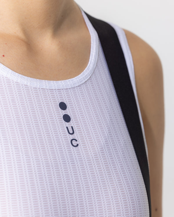 Neckline close-up on model: scoop-neck white binding and navy UC chest mark on the Women's Mono Sleeveless Base Layer.