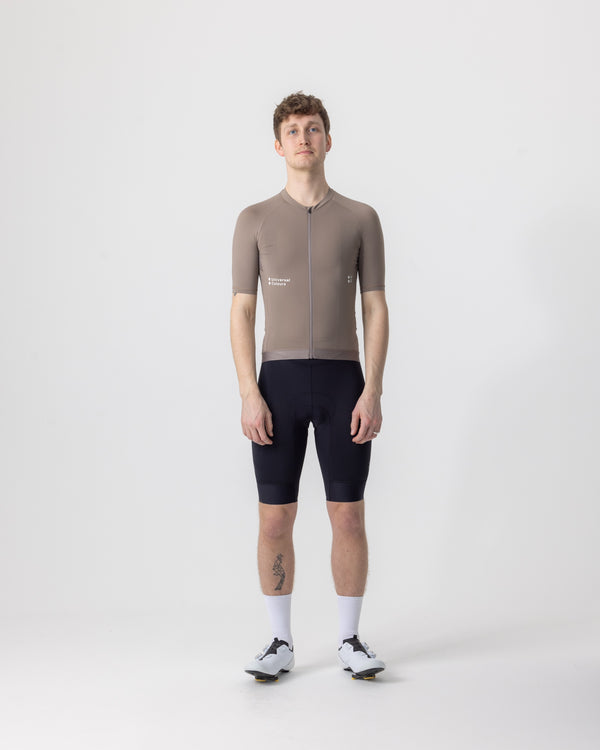 Model wearing the Men's Mono Short Sleeve Jersey in Portobello Grey, front view, paired with black cycling bib shorts.