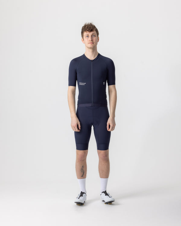 Model wearing the Men's Mono Short Sleeve Jersey in Navy Blue, front view, paired with matching navy bib shorts.