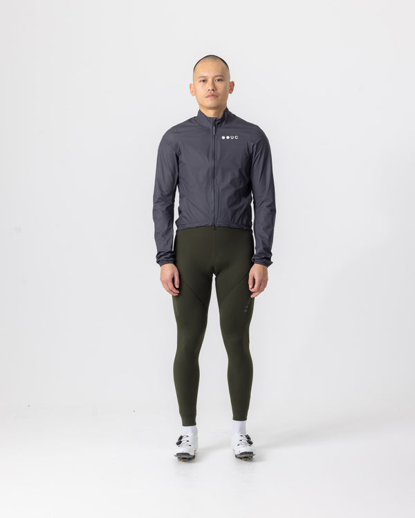 Model wearing the Men's Mono Rain Jacket in Black, front view, paired with olive green cycling bib tights.