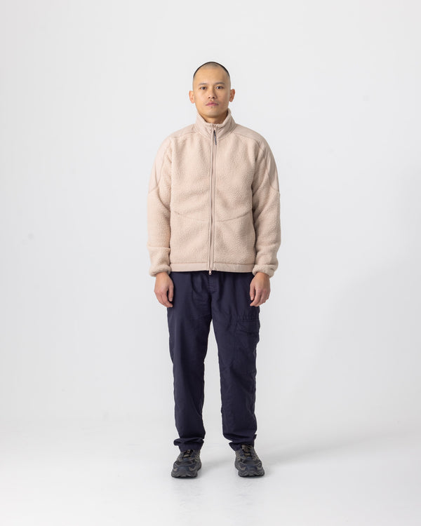 Model wearing the Almond Beige Fleece Jacket, front view, styled with navy ripstop trousers and dark trail trainers.