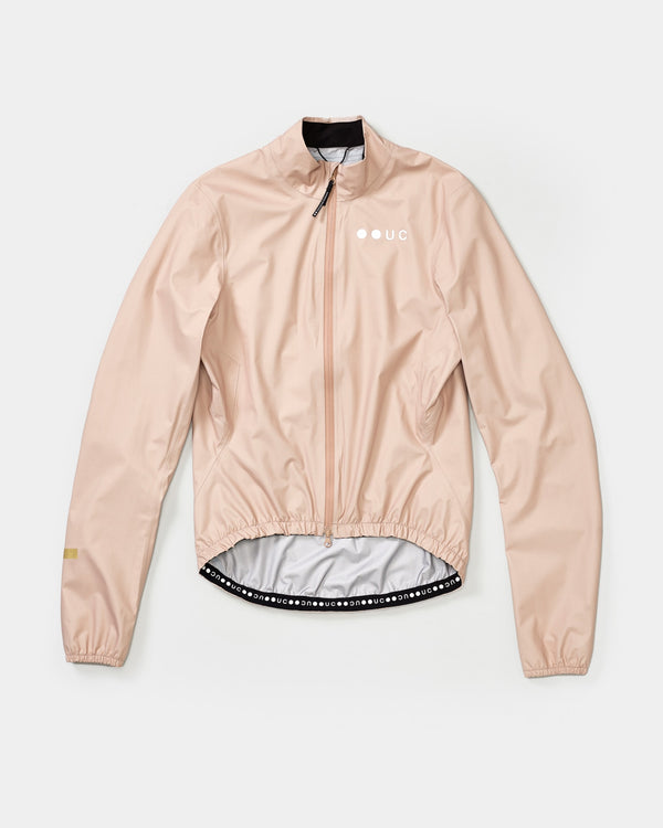 Women's Mono Rain Jacket in Almond Beige flatlay: ripstop fabric, full-length zip, white UC chest logo and dot-wordmark hem.