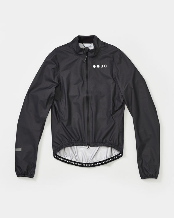 Women's Mono Rain Jacket in Black flatlay: ripstop fabric, full-length zip, white UC chest logo and dot-wordmark hem.