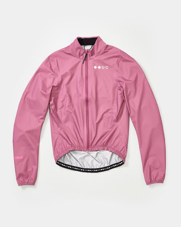 Flatlay of the Women's Mono Rain Jacket in Soft Pink: high collar, full-length zip, tonal UC chest logo, elasticated hem.