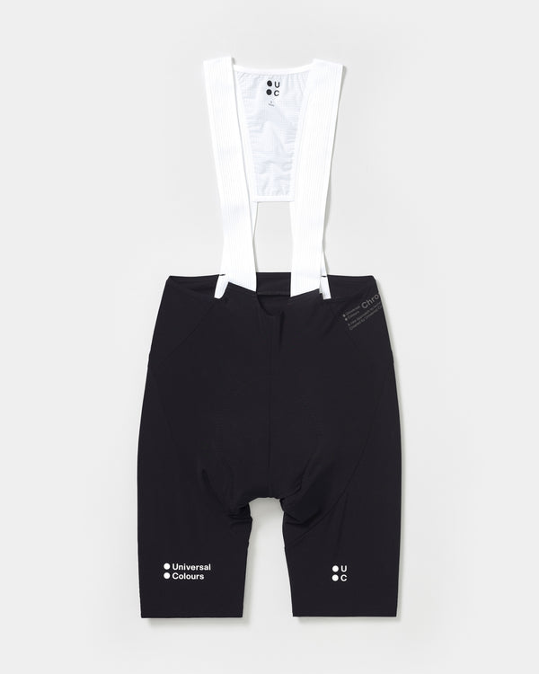 Flatlay of the Men’s Chroma Bib Shorts in Black with white ribbed bib straps and tonal UC and Universal Colours leg logos.