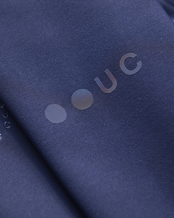 Close-up of the tonal Universal Colours roundel logo at the wrist of the UC Arm Warmers in Navy Blue.