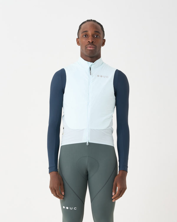 Model wearing the Unisex Chroma Insulated Gilet in Misty Blue over a navy base layer and sage green bib tights.