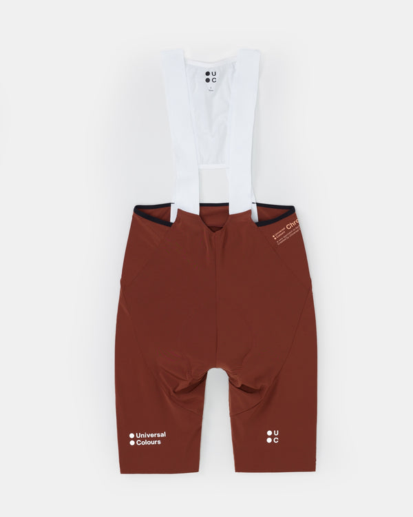Flatlay of the Men's Chroma Bib Short in Brick Red: white mesh bib upper, navy waistband and tonal Chroma wordmark.