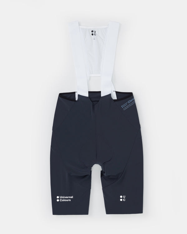 Flatlay back view of the Men's Chroma Bib Short in Navy Blue with white mesh bib straps and contrast UC leg branding.