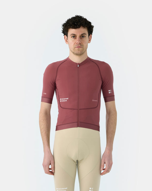 Model wearing the Men's Chroma Short Sleeve Jersey in Jaipur Red, front view, paired with cream UC bib shorts.
