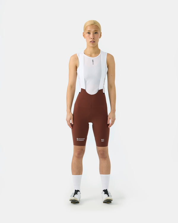 Model wearing the Women's Chroma Bib Shorts in Brick Red, front view, styled with a white mesh base layer.